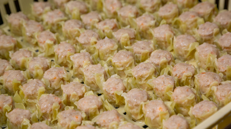 An enormous, mass quantity of cooked shumai rest on a rack.