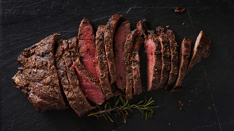 A sliced rare steak on a brown background