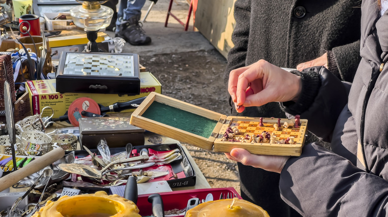 A person going through various items at a yard or estate sale outdoors.