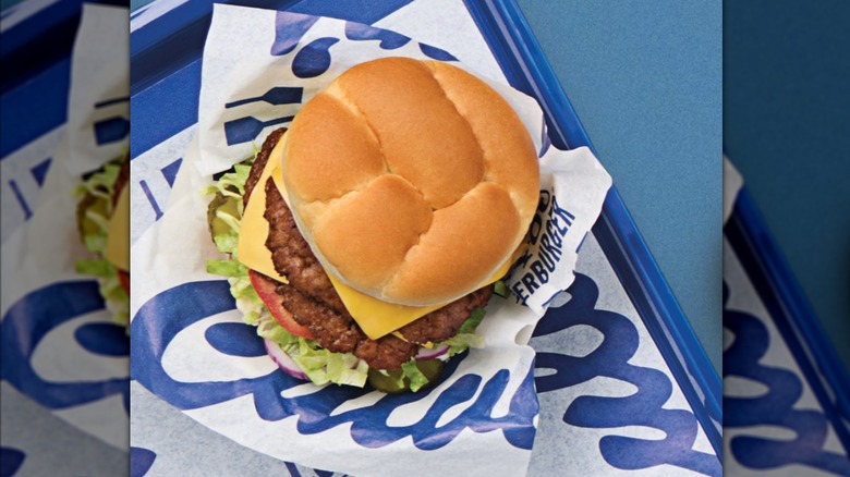 Culver's deluxe burger on a branded paper on blue tray