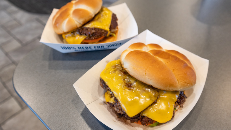 Two butter burgers from Culver's in white paper dishes on gray table