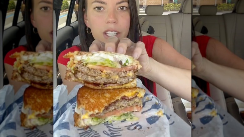 Woman holding up cross section of ButterBurger on sourdough bread.