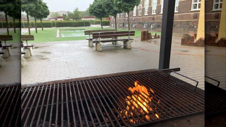 The view from behind a burning charcoal grill under a shelter on a rainy day