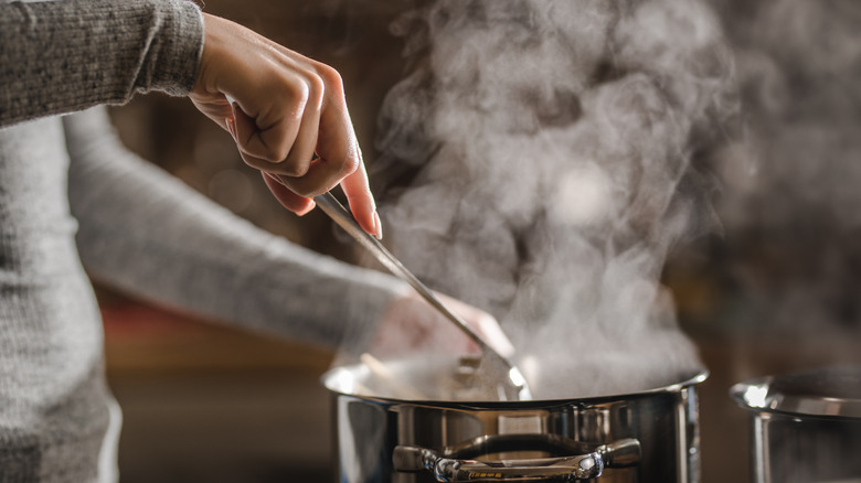 Person stirring spaghetti in pot