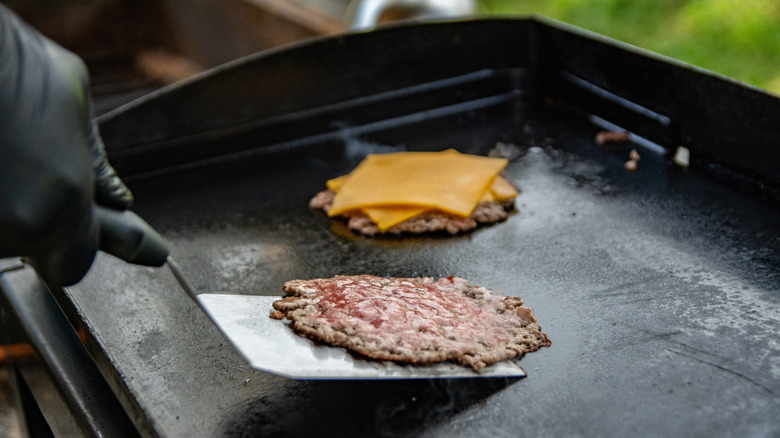 A cook flipping burger with spatula