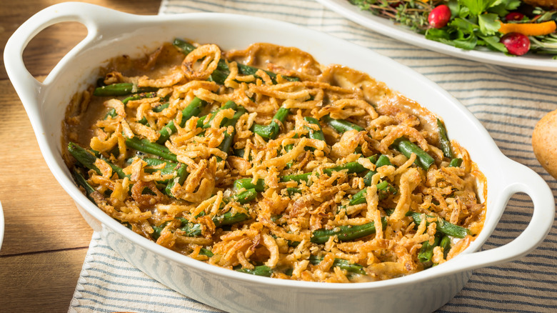 Green bean casserole in oval white casserole dish sitting on a table