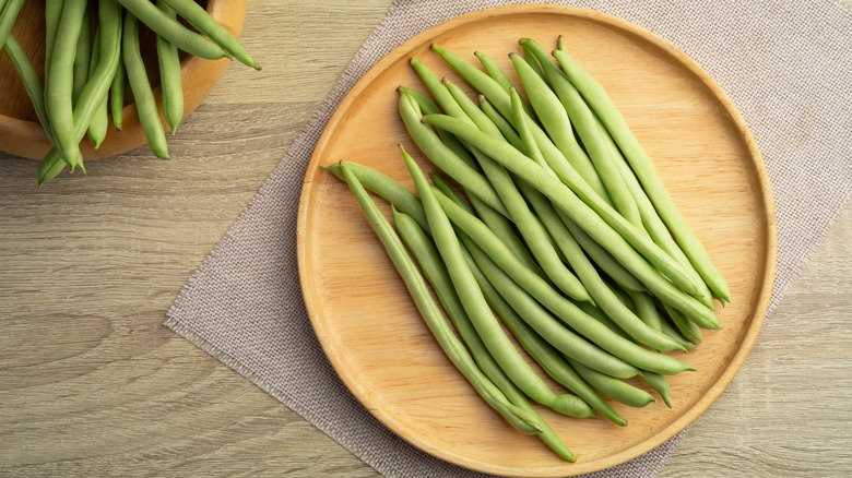 Fresh green beans on a round wooden plate