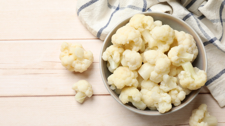 Tasty cooked cauliflower on white wooden table, top view. Space for text