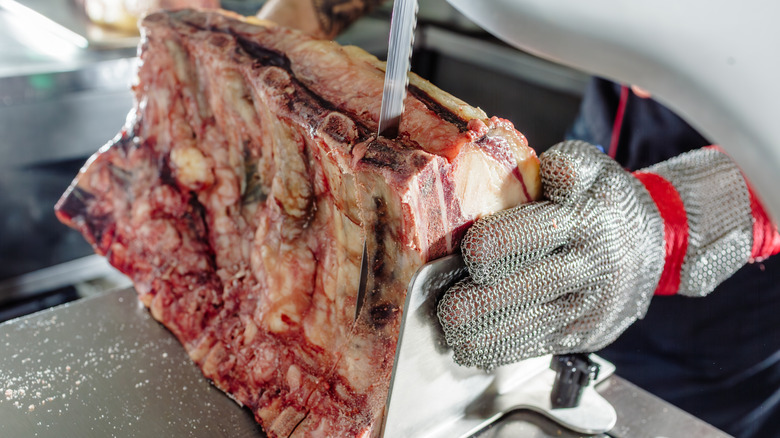 Ribeye steaks are being sliced apart with a large knife.