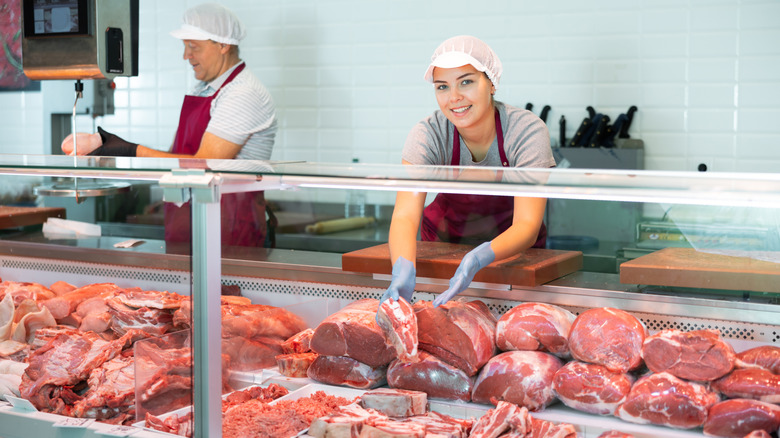 Butchers are seen working behind a meat counter.
