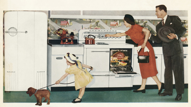1950s photo of woman cooking in a dress, with husband and kid nearby.