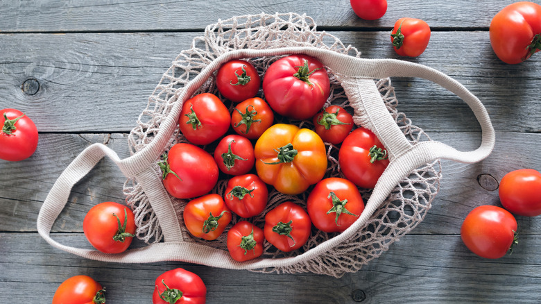 Tomatos in open knit bag on wooden table