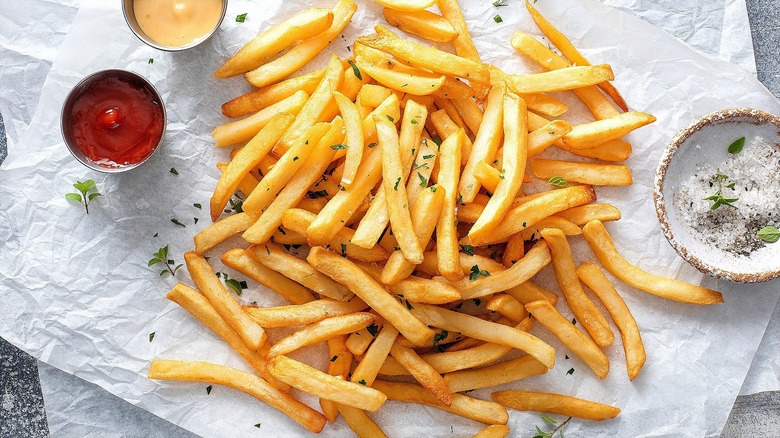 Large serving of cooked fries on layered sheets of parchment paper