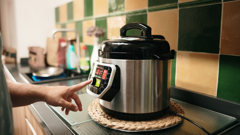 A person pushing a button on a slow cooker