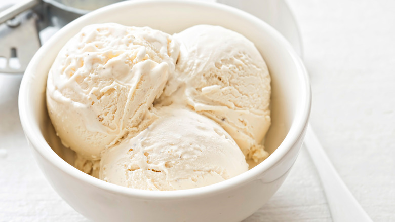 A white bowl with three scoops of vanilla ice cream