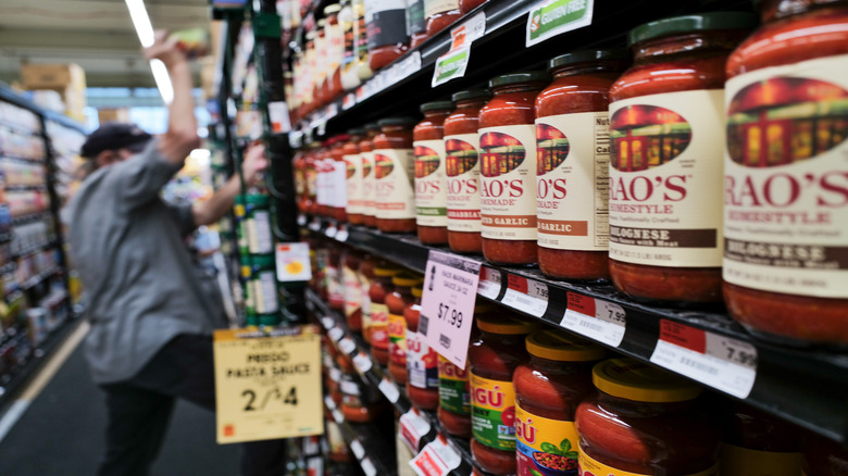 Jars of pasta sauce lined up in a grocery store aisle