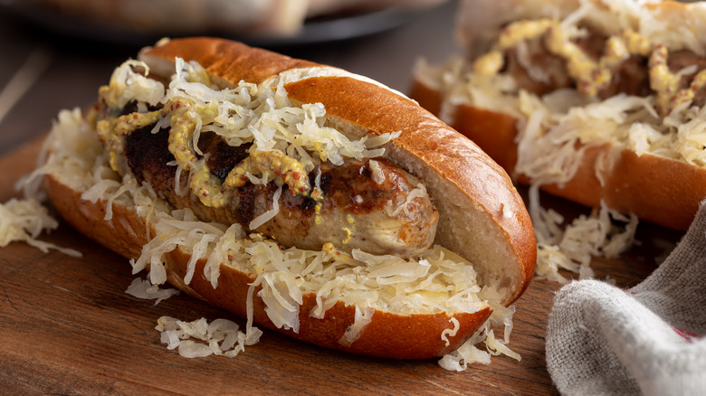 A bratwurst on a bun with braised cabbage and mustard.