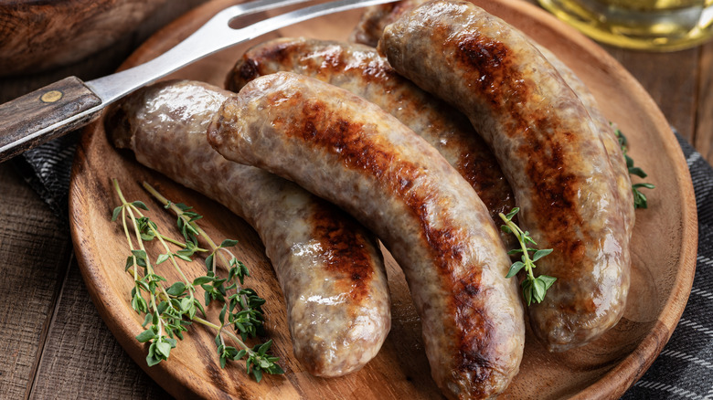A plate of grilled brats arranged with herbs.