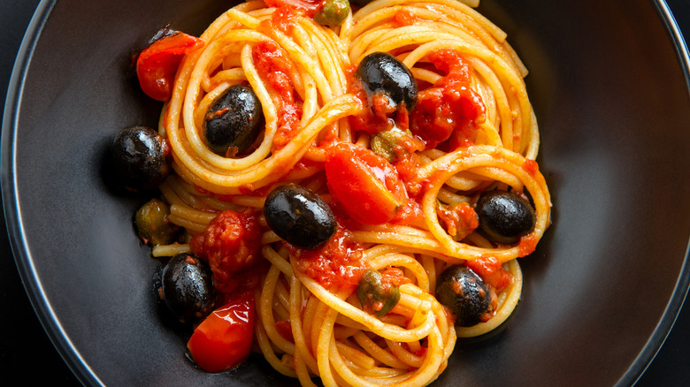 pasta puttanesca in a black bowl