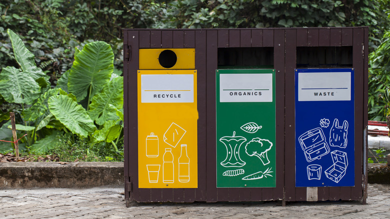 A trash disposal site with three bins, one for organic waste