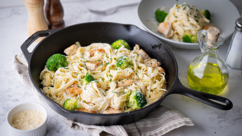 A skillet of fettucine Alfredo with chicken and broccoli