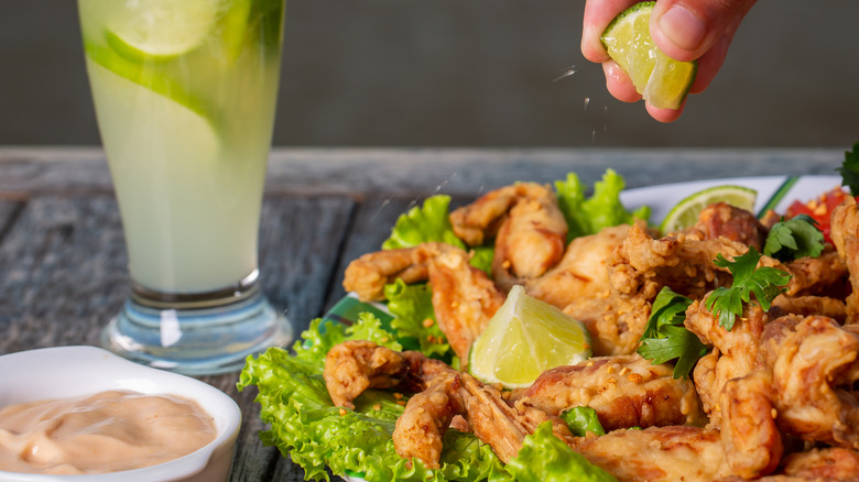 A person squeezing lime on fried frog legs