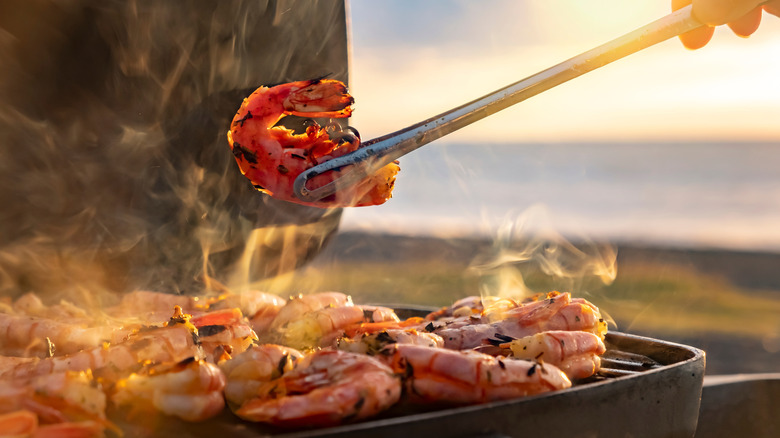 A person grilling shrimp on a barbecue