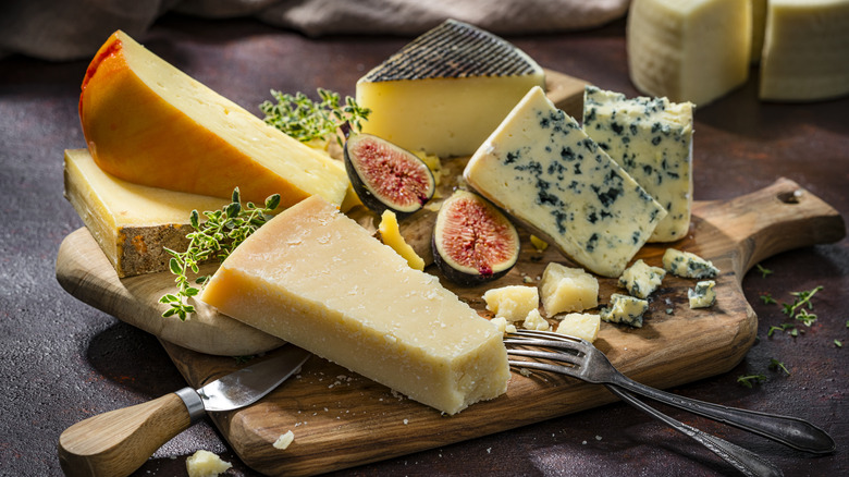 Assorted cheeses on wooden board with forks