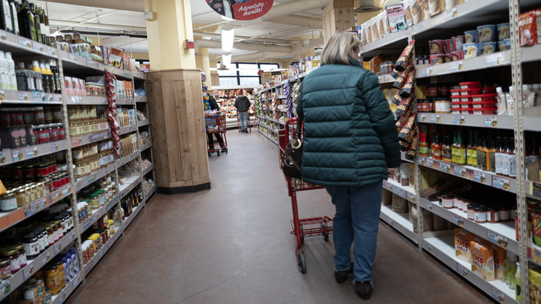 A woman in a green down vest looks at grocery items in a Trader Joe's