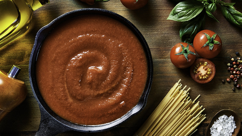 Tomato sauce in a cast iron pan on a wooden table.