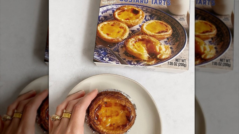 A hand holding a Trader Joe's Portuguese Custard Tart besides the package