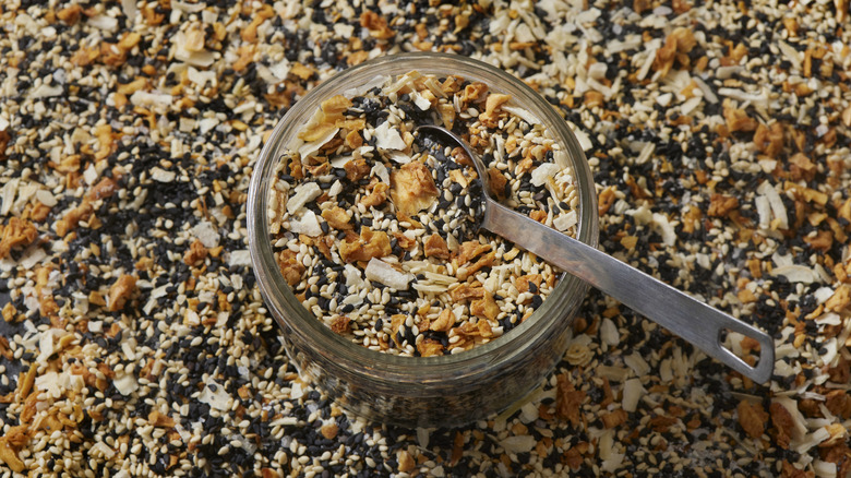 Everything but the bagel seasoning in clear jar with measuring spoon on top of seasoning blend.