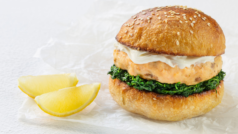 salmon burger with spinach, creamy spread, and lemon on the side