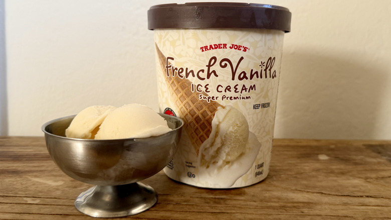 French vanilla ice cream in stainless steel dish next to its container on a wooden table
