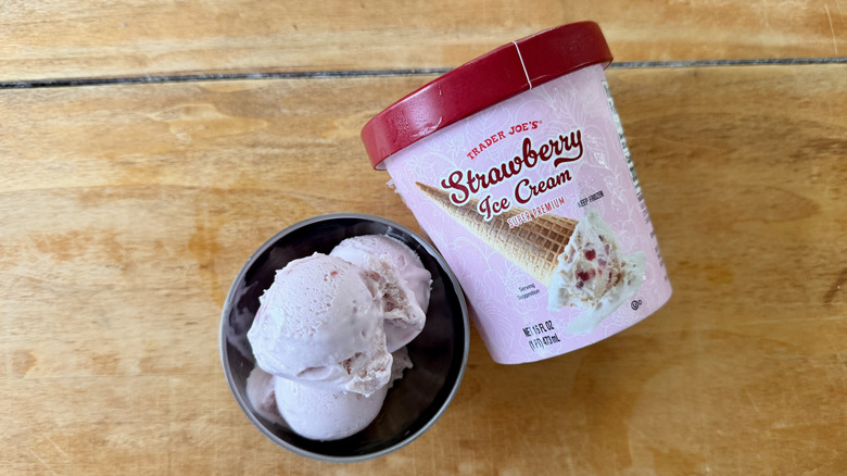 Strawberry Ice Cream in stainless steel dish next to its container on a wooden table