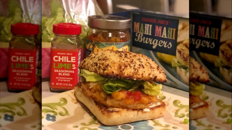 A prepared mahi mahi burger from Trader Joe's next to the branded box and a container of chili lime seasoning