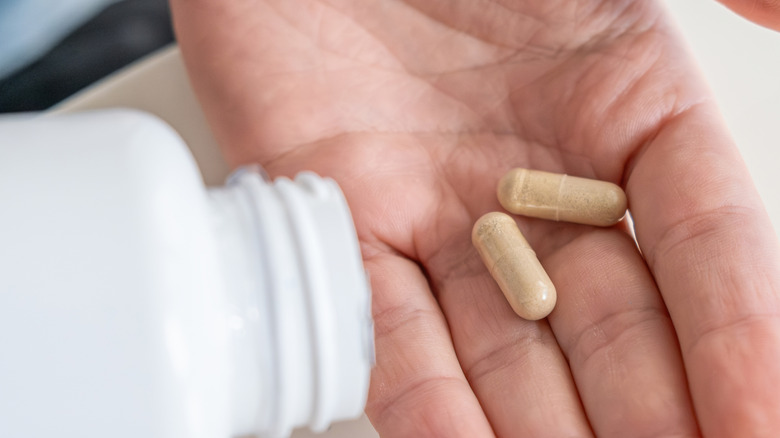 Pouring probiotic capsules into a man's hand