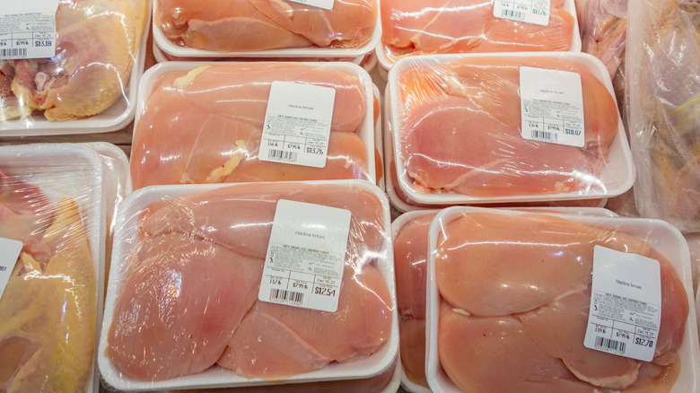 Various cuts of raw chicken packaged and on display in a grocery store