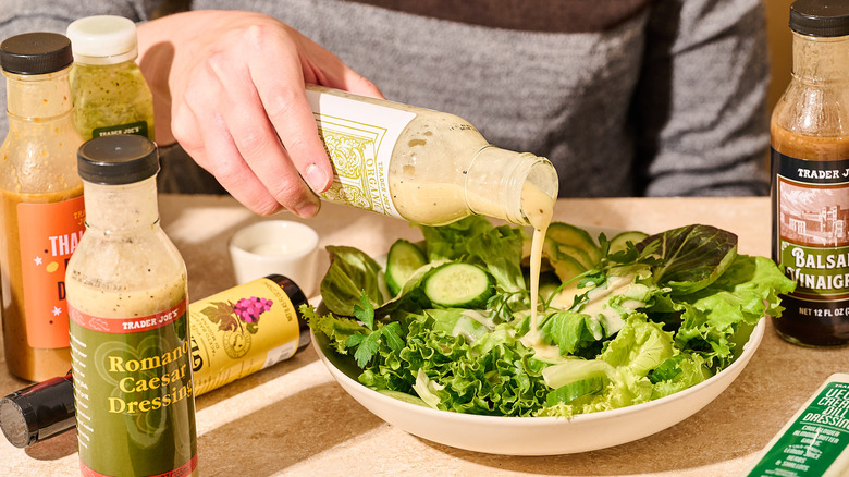 pouring salad dressing over a salad