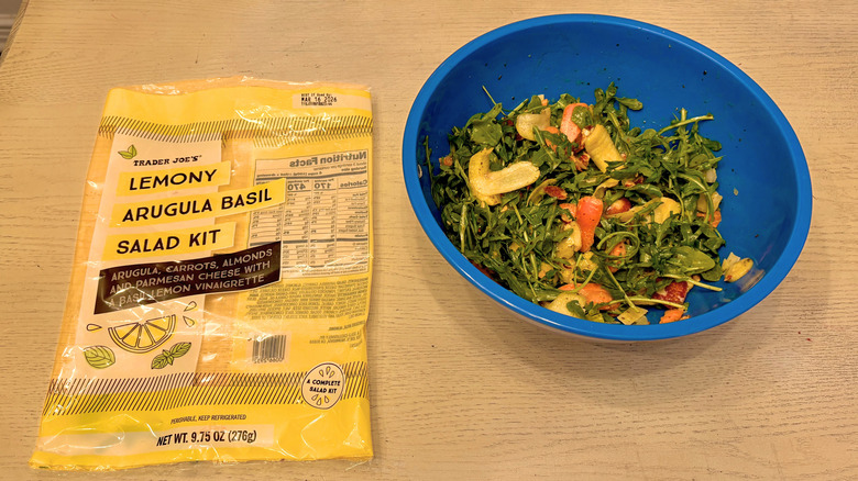 A prepared Lemony Arugula Basil Salad next to its bag