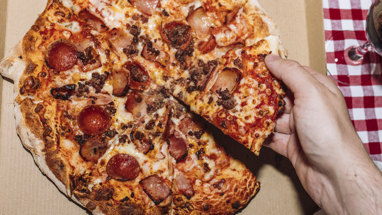 Hand picks up a piece of pizza