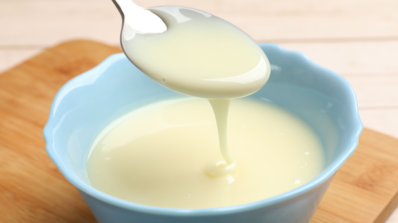 Spoonful of condensed milk hovering over a bowl