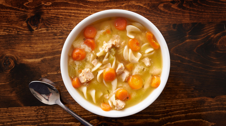 Chicken noodle soup in white bowl on a wooden table