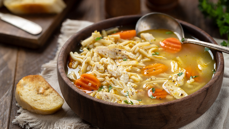 Wooden bowl of chicken noodle soup.