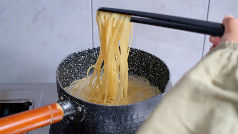 Person cooking spaghetti in pot