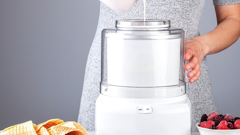 Hand pouring cream into a white ice cream machine