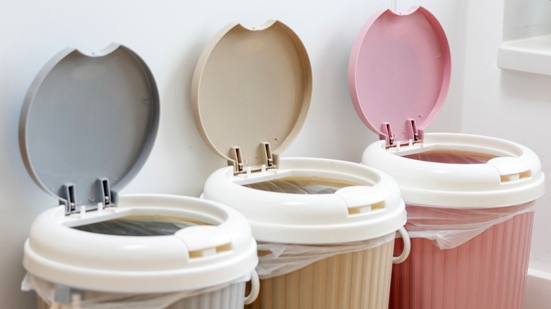 Gray, beige, and pink trash can in a row