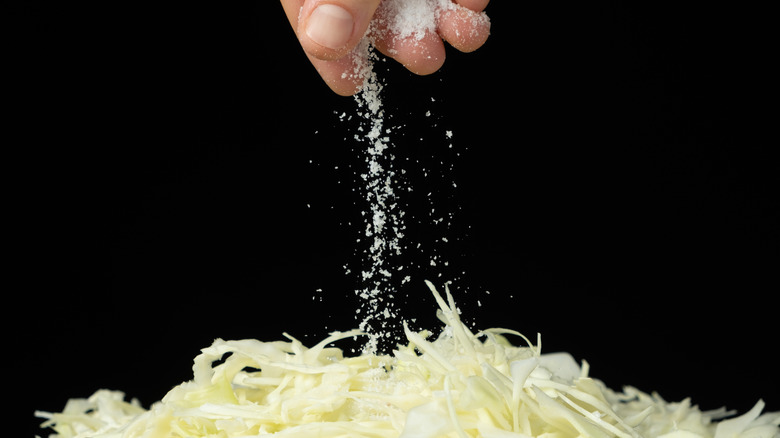 Sprinkling salt on chopped cabbage.