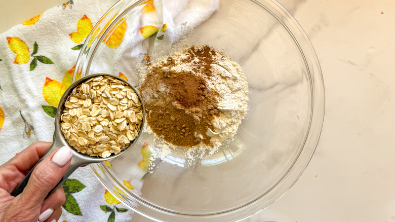 hand adding oats to bowl