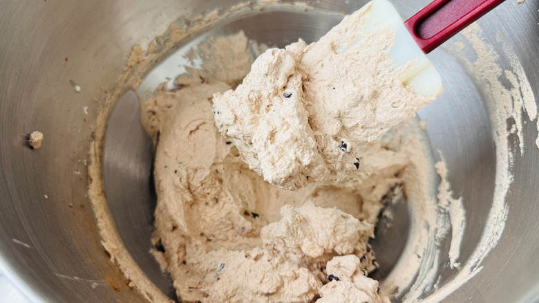 Spatula holding chocolate cream filling above more filling in bowl